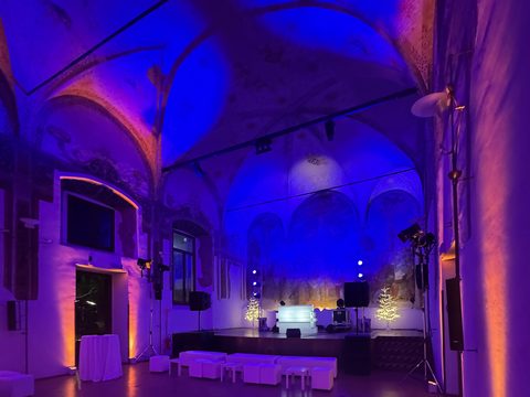 Allestimento luci scenografico in sala storica con volte, luce blu e viola